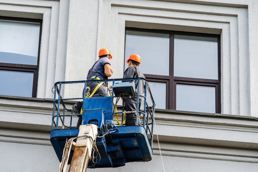 Two Construction Workers in Orange Helmets on a Lift — BK Painting & Property Maintenance in Gracemere, QLD