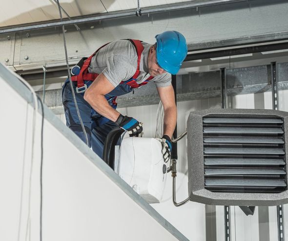 A man is working on a heater in a building.