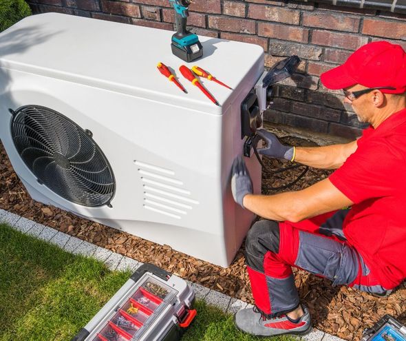 A man in a red shirt is working on an air conditioner.