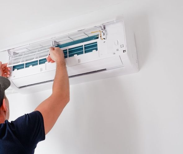 A man is cleaning a wall mounted air conditioner.