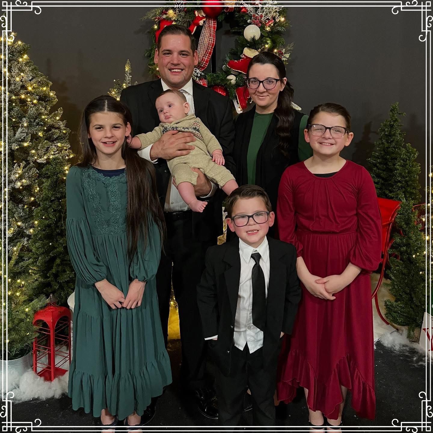 A family is posing for a picture in front of a christmas tree.