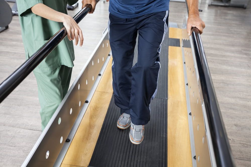 A Nurse Is Helping a Man Walk on A Treadmill — Illawarra Sports Injury Rehabilitation and Physiotherapy Centre in Bellambi, NSW