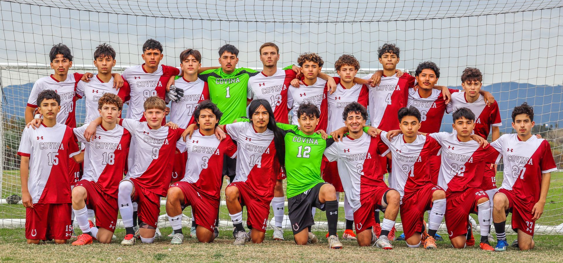 Youth soccer team posing for a group photo in red and white uniforms, with a coach in neon green at center.