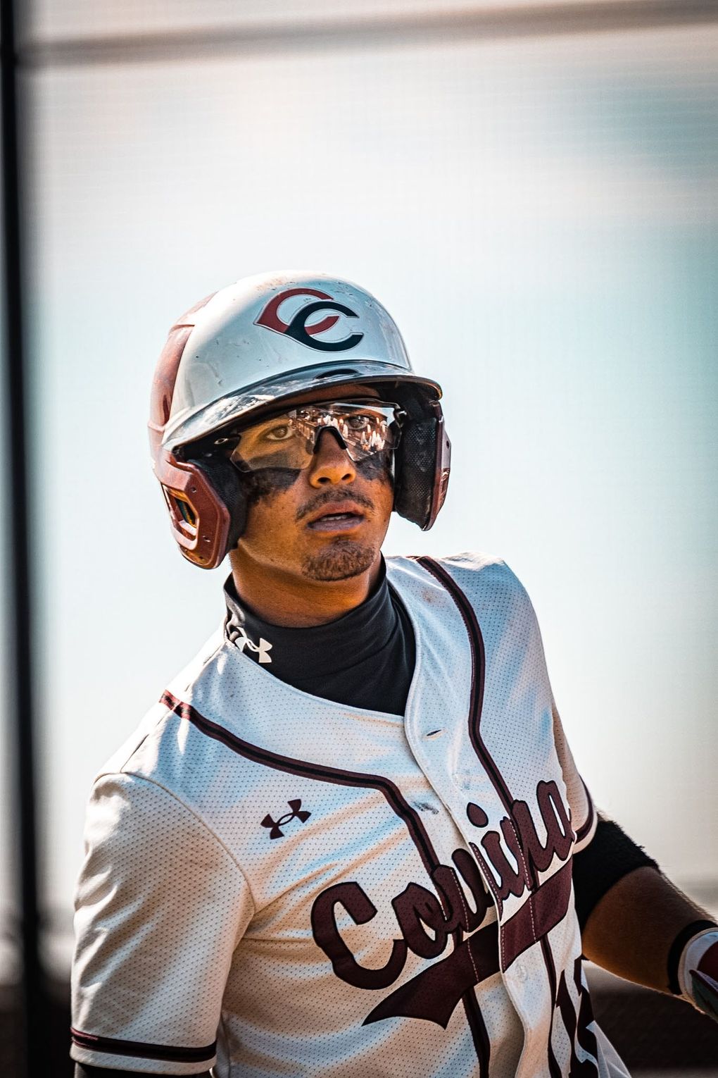 Baseball player in a white pinstriped jersey and helmet, looking to the side while running