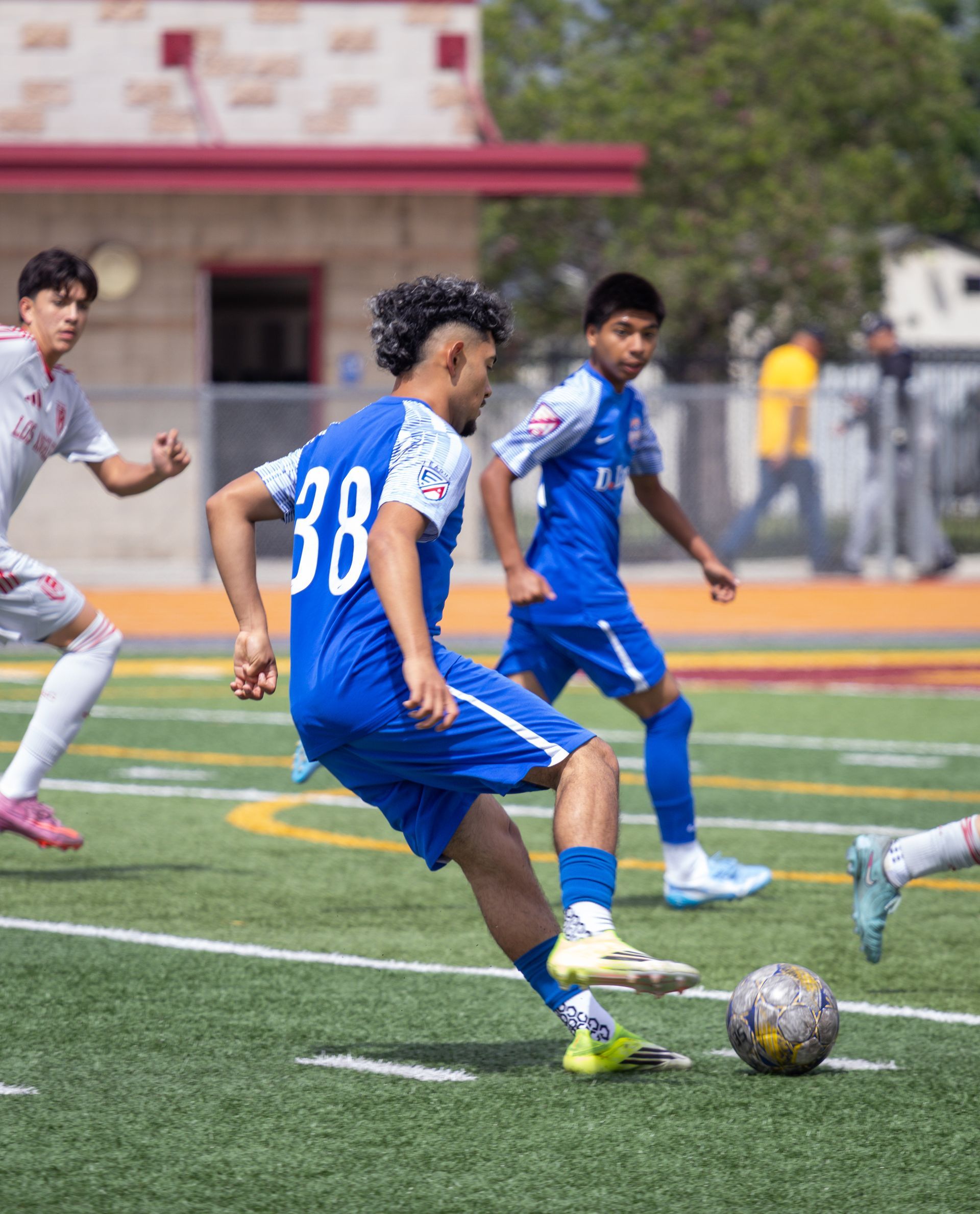 Soccer players in blue and white jerseys compete for the ball on a grassy field.