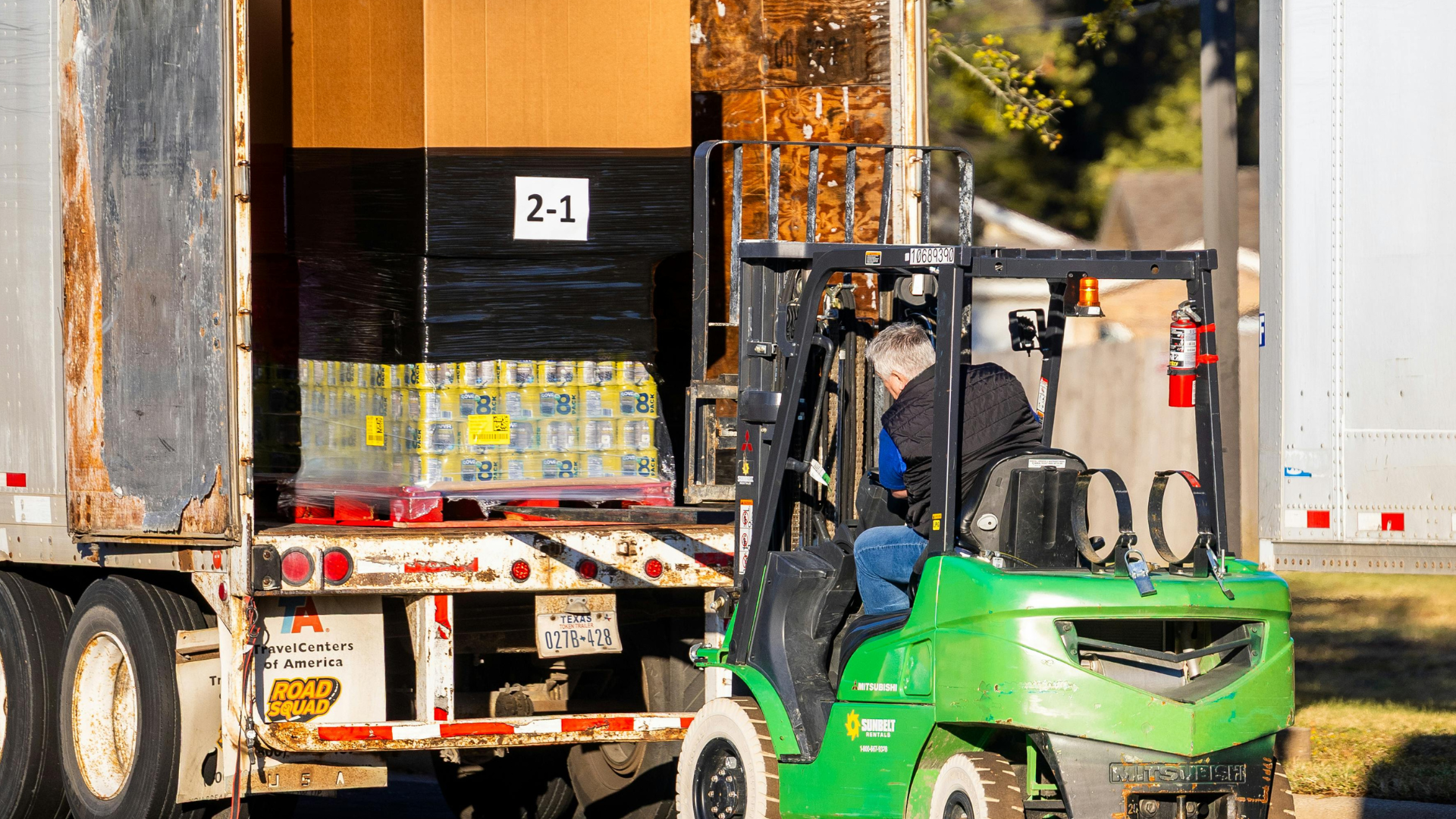 Electrician in a blue shirt working on a breaker panel inside a wooden wall.