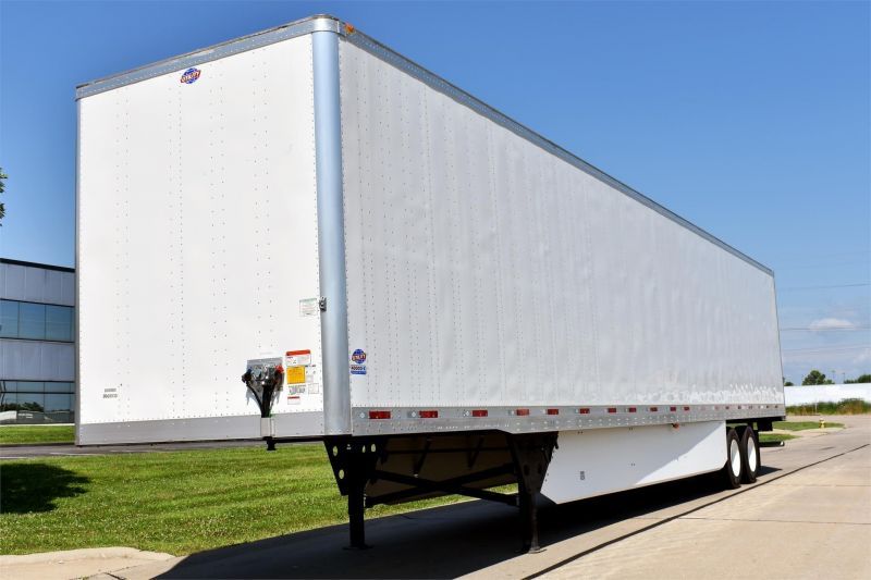 A white trailer is parked on the side of the road.
