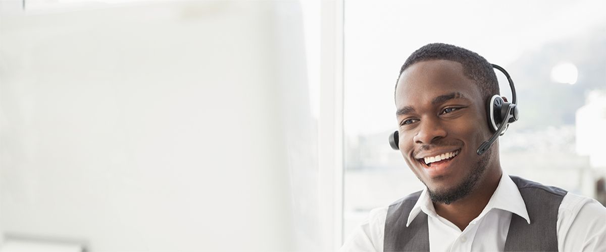 A man wearing a headset is sitting in front of a computer.