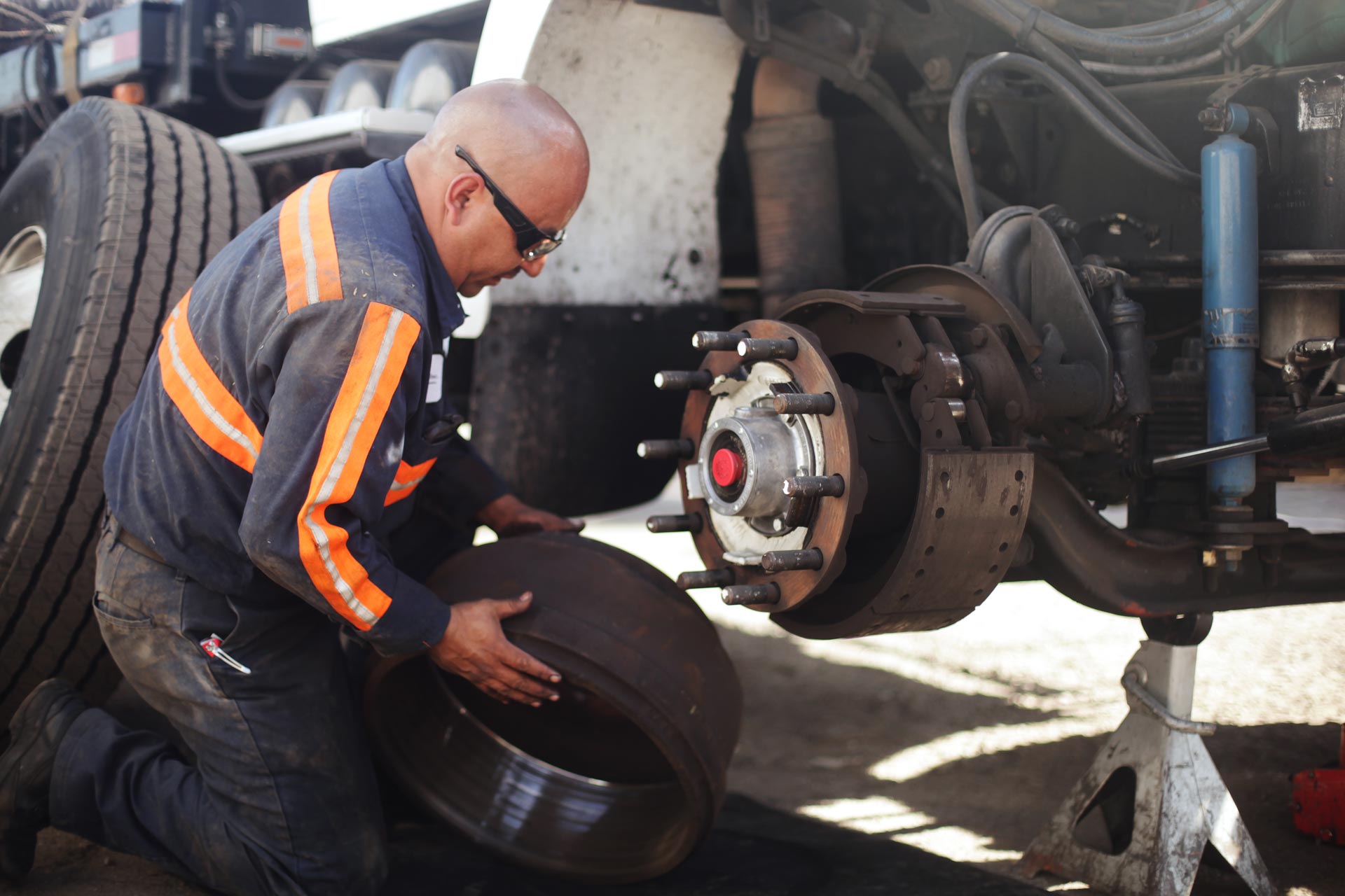 A man is kneeling down to change a tire on a truck.