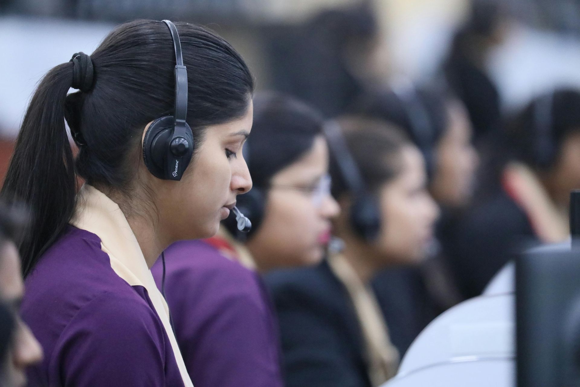 People wearing headsets in a call center, focused on their work.