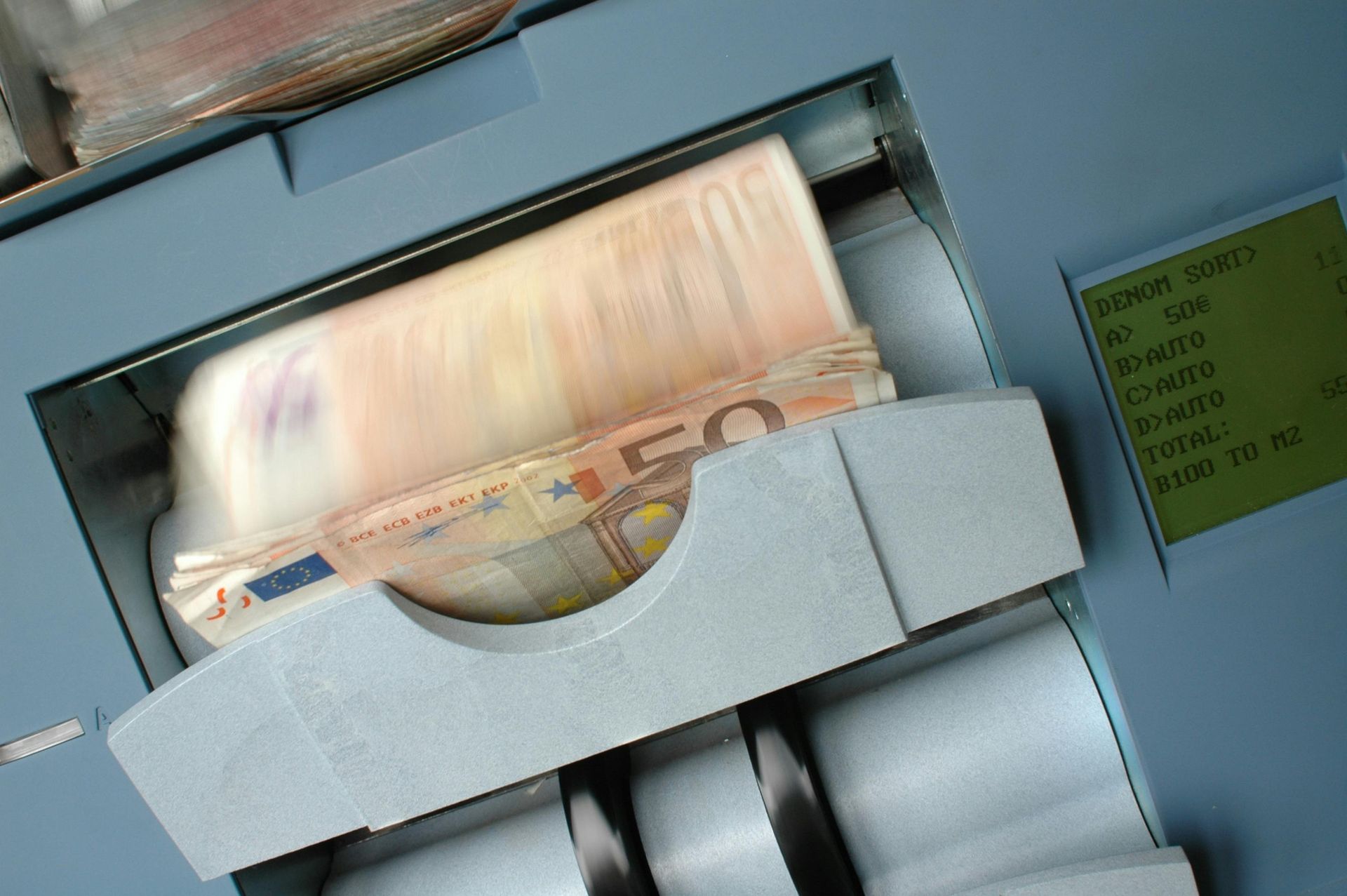Money counting machine in operation; fifty euro banknotes visible, counting.