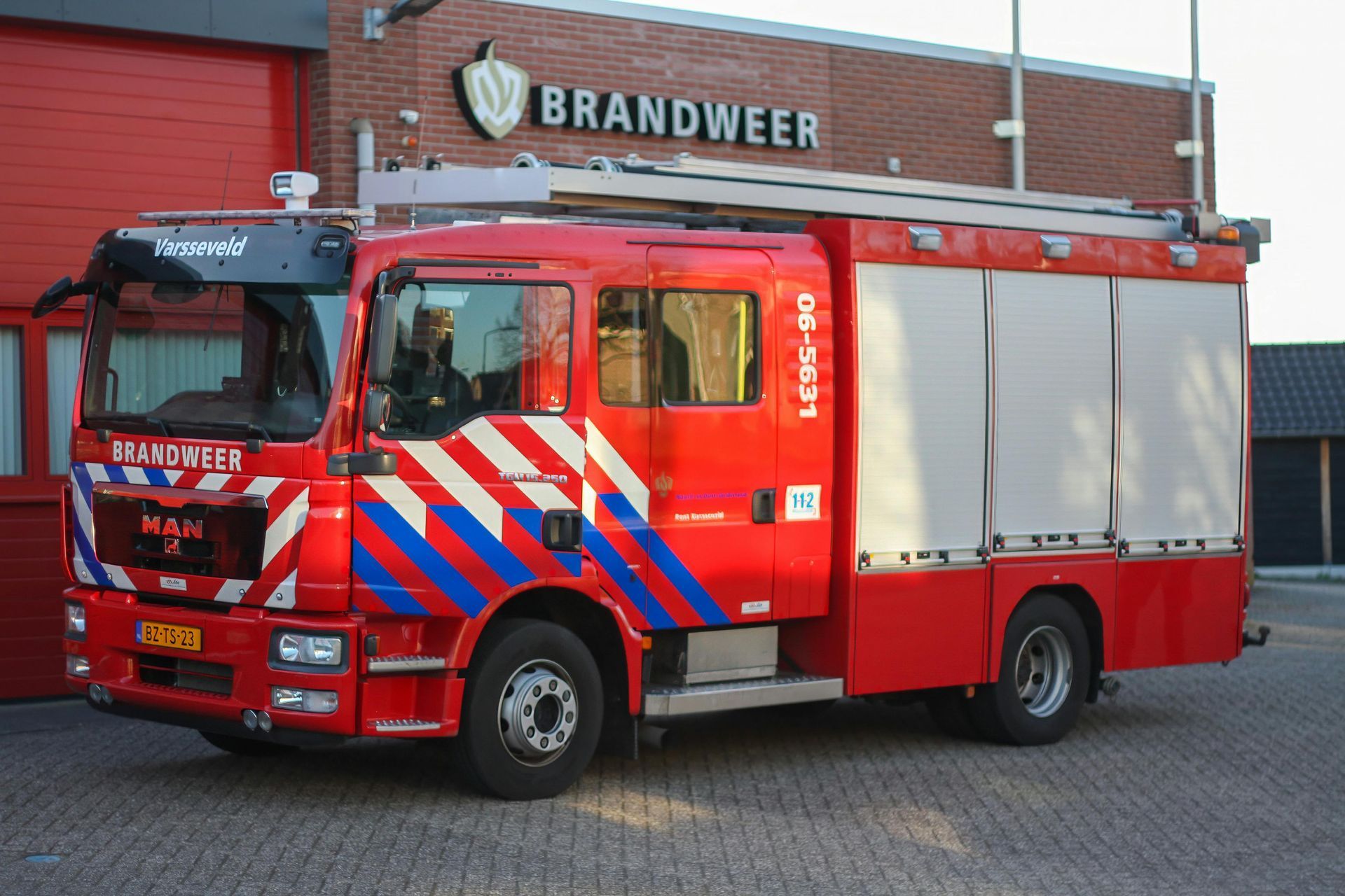 Red Dutch fire truck parked in front of a fire station.