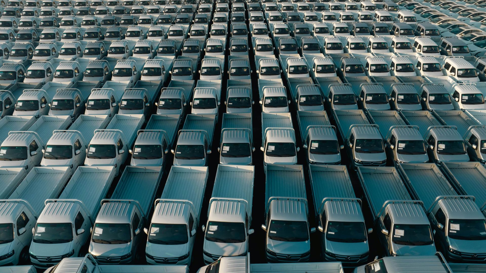 Rows of white vans parked closely together in an outdoor lot.