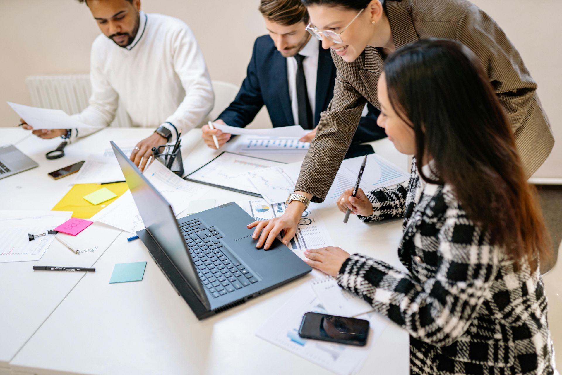 Business team at a table, discussing documents and a laptop, in an office.
