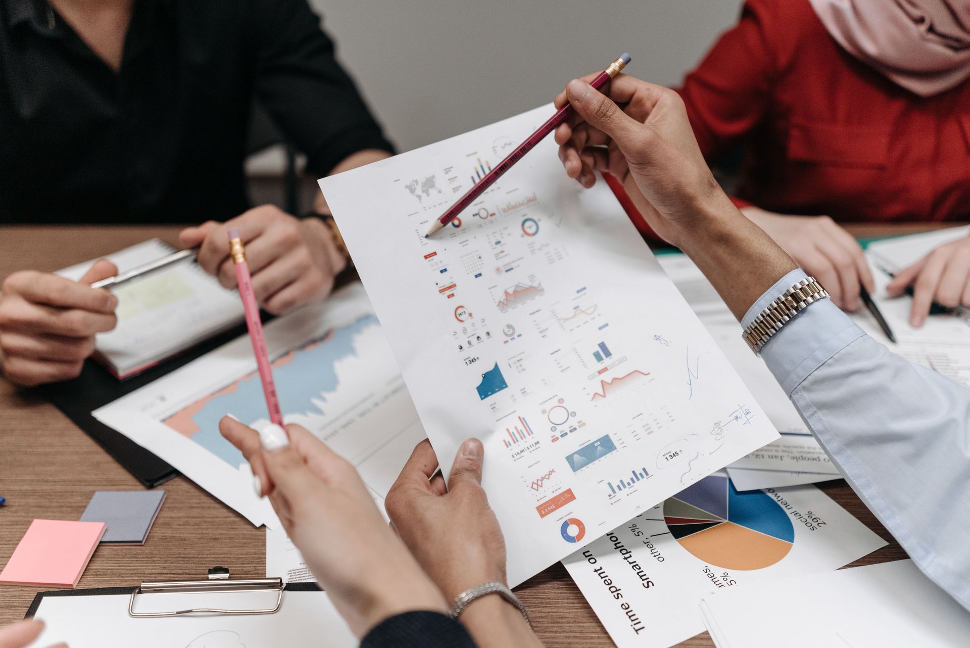 People reviewing charts and graphs on printed reports around a conference table
