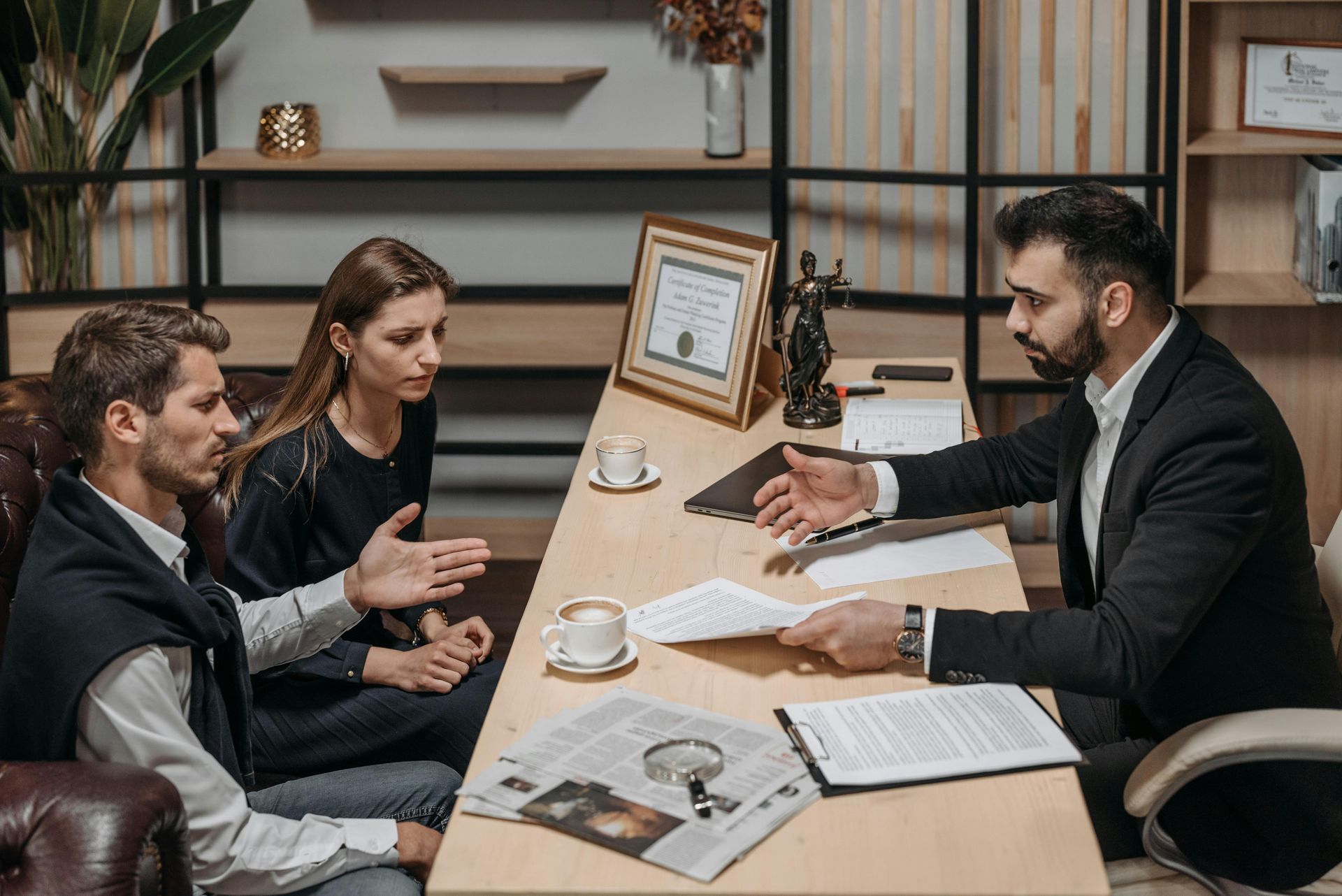 A couple consults with a lawyer at a desk in a law office.