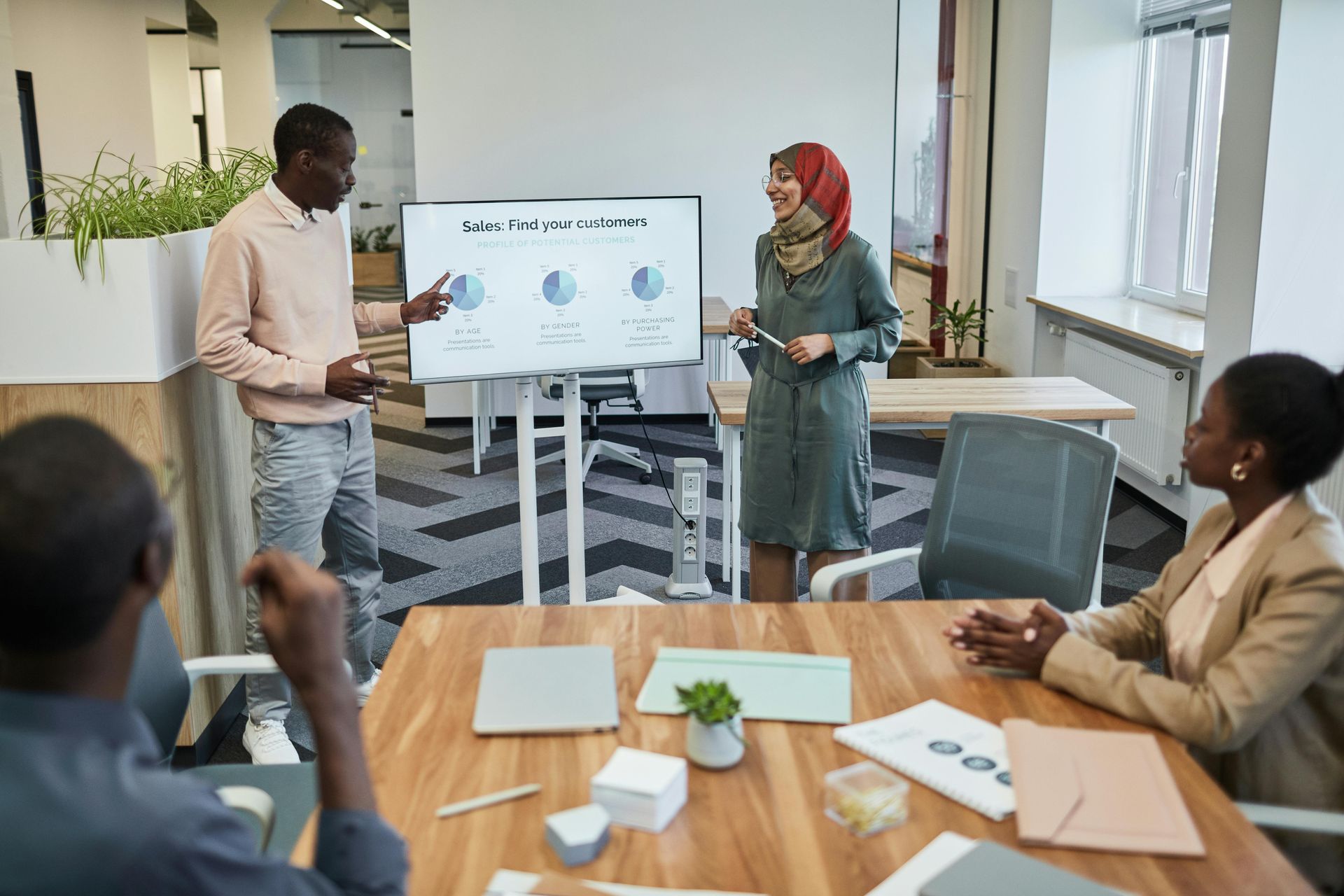 A team discusses data shown on a screen in a modern office meeting room.