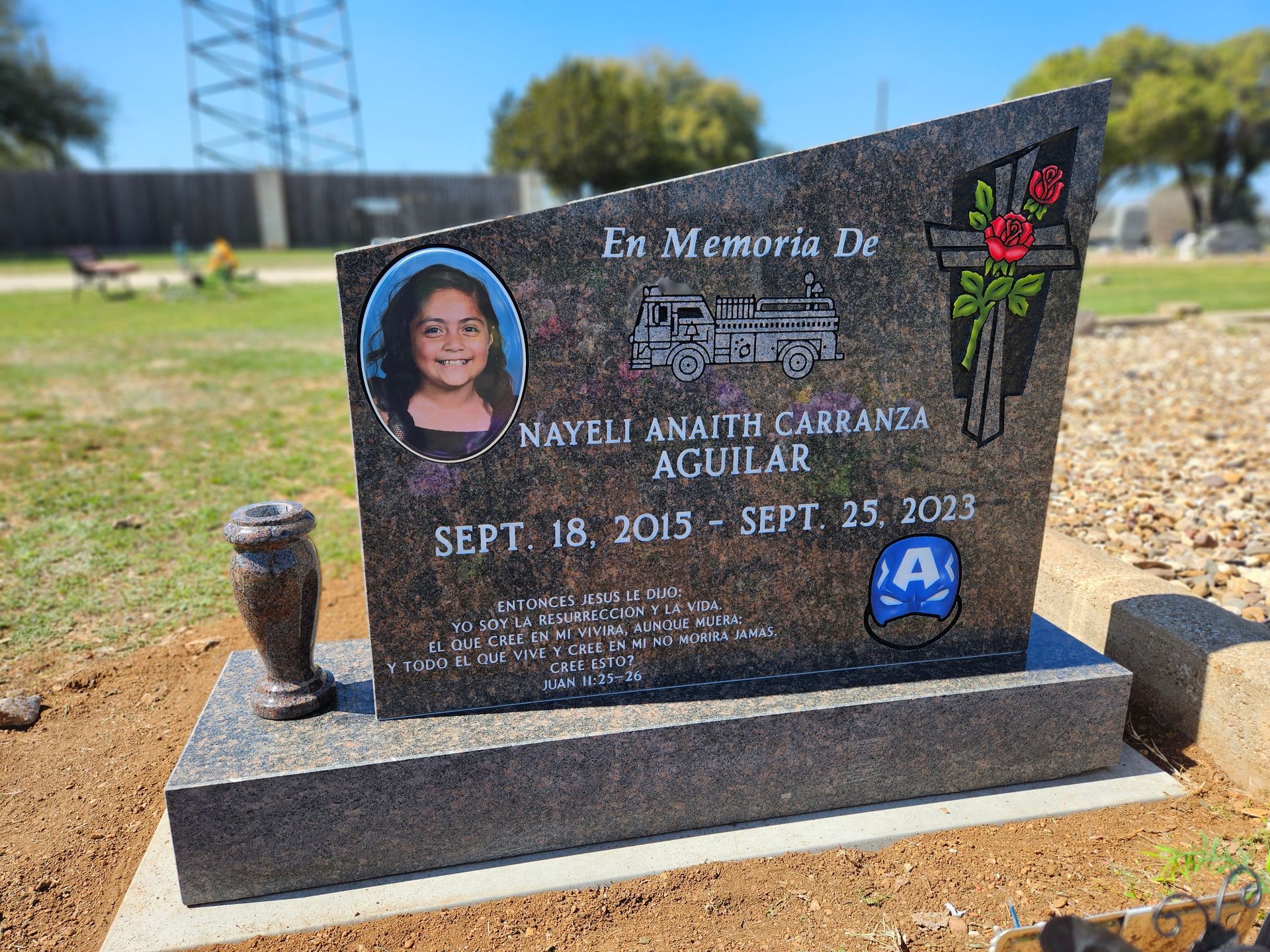 A gravestone with a picture of a little girl on it in a cemetery.
