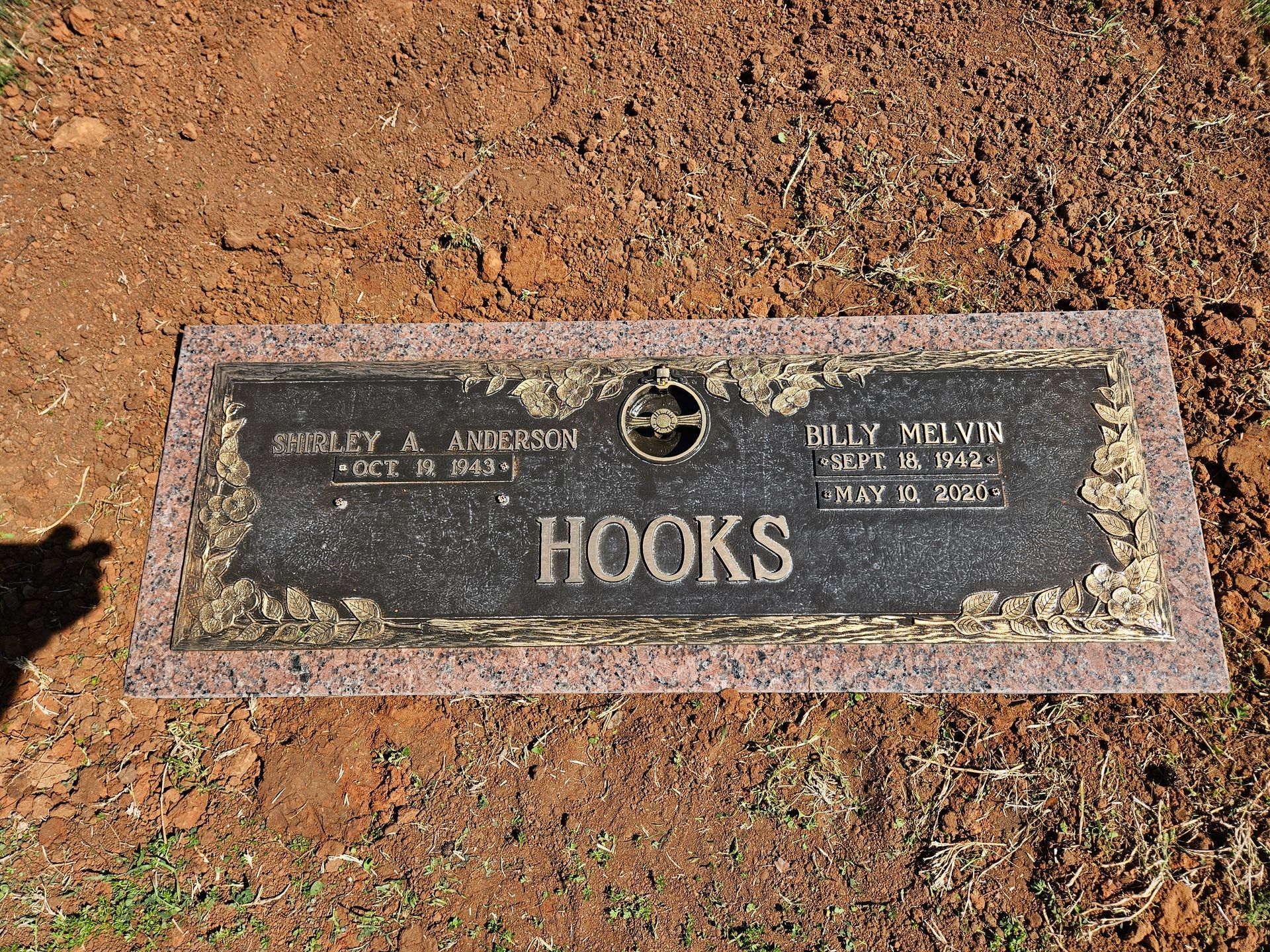 A gravestone for hooks is sitting in the dirt.