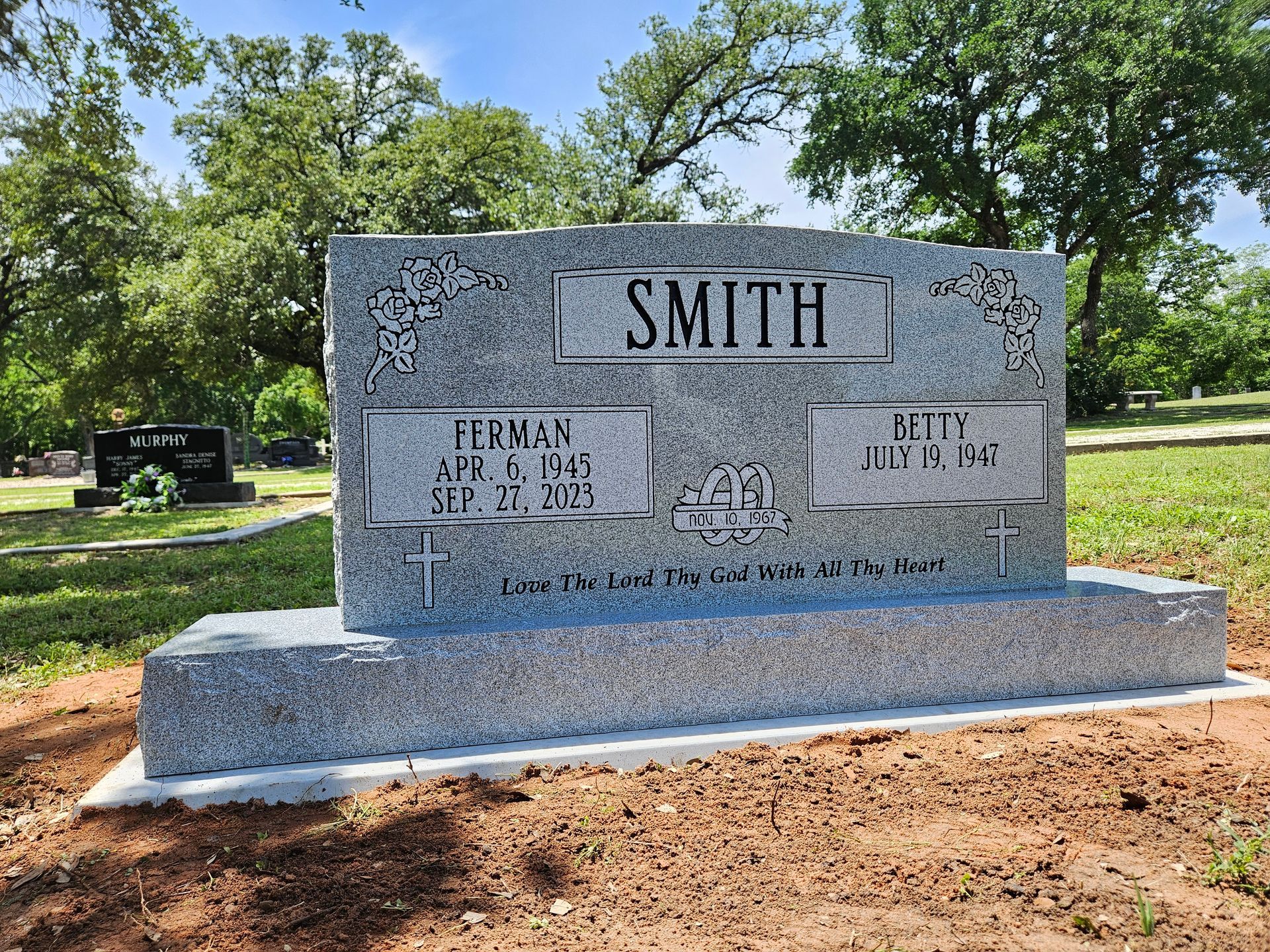 A gravestone for smith in a cemetery with trees in the background.