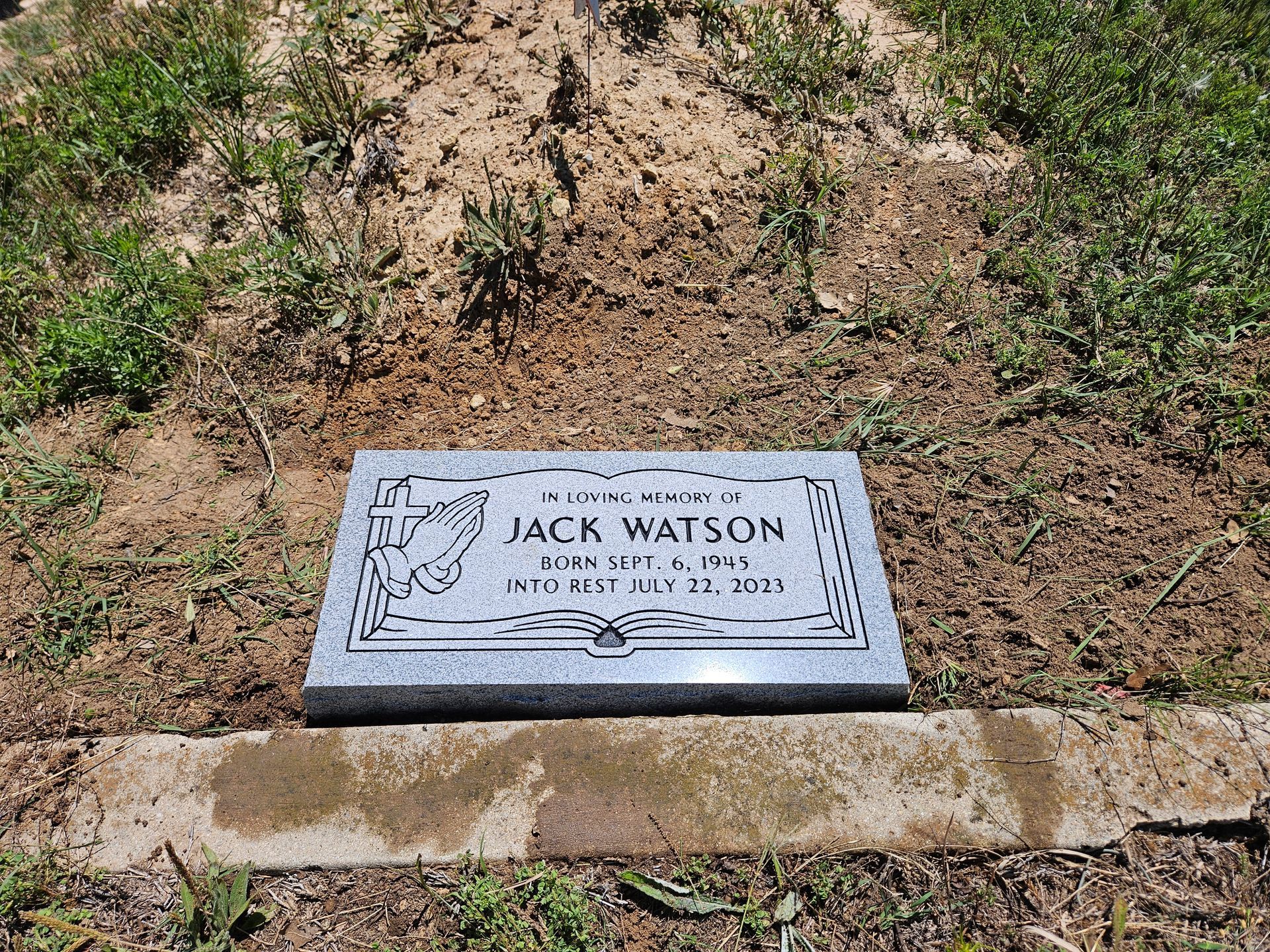 A gravestone for jack watson is in the middle of a grassy field.