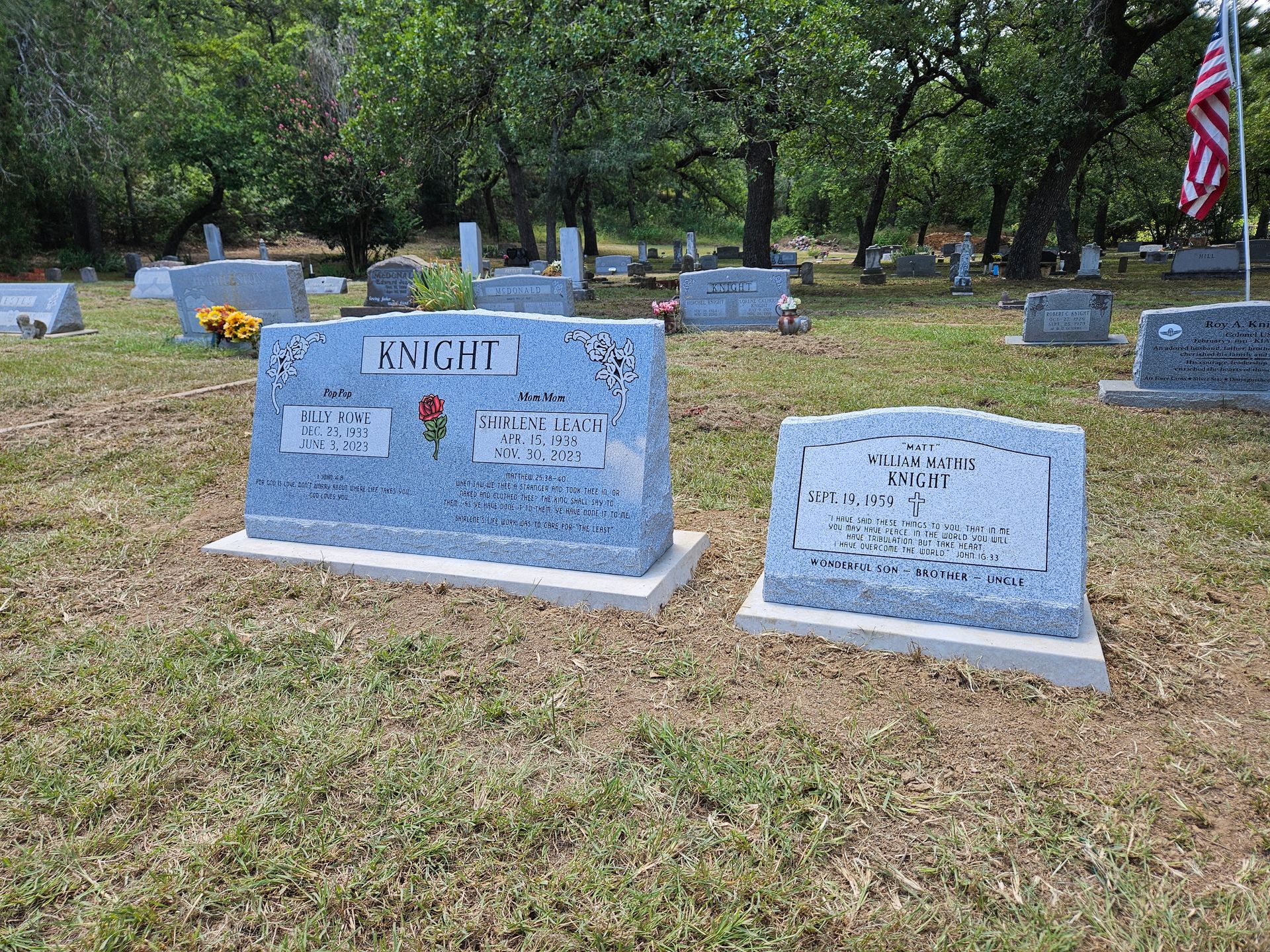 A couple of graves in a cemetery with a flag in the background.