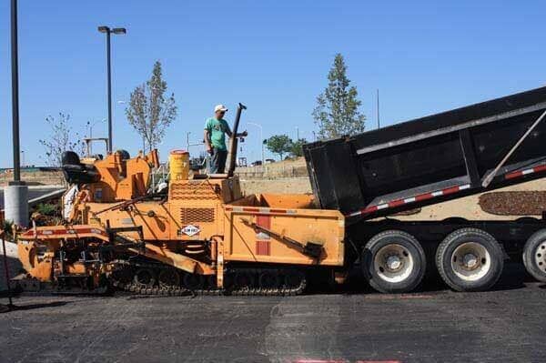 A man is standing on top of a dump truck.
