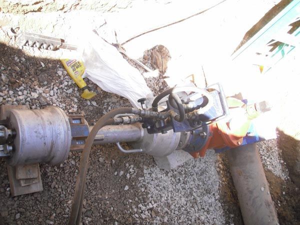 A machine is sitting on the ground next to a pipe
