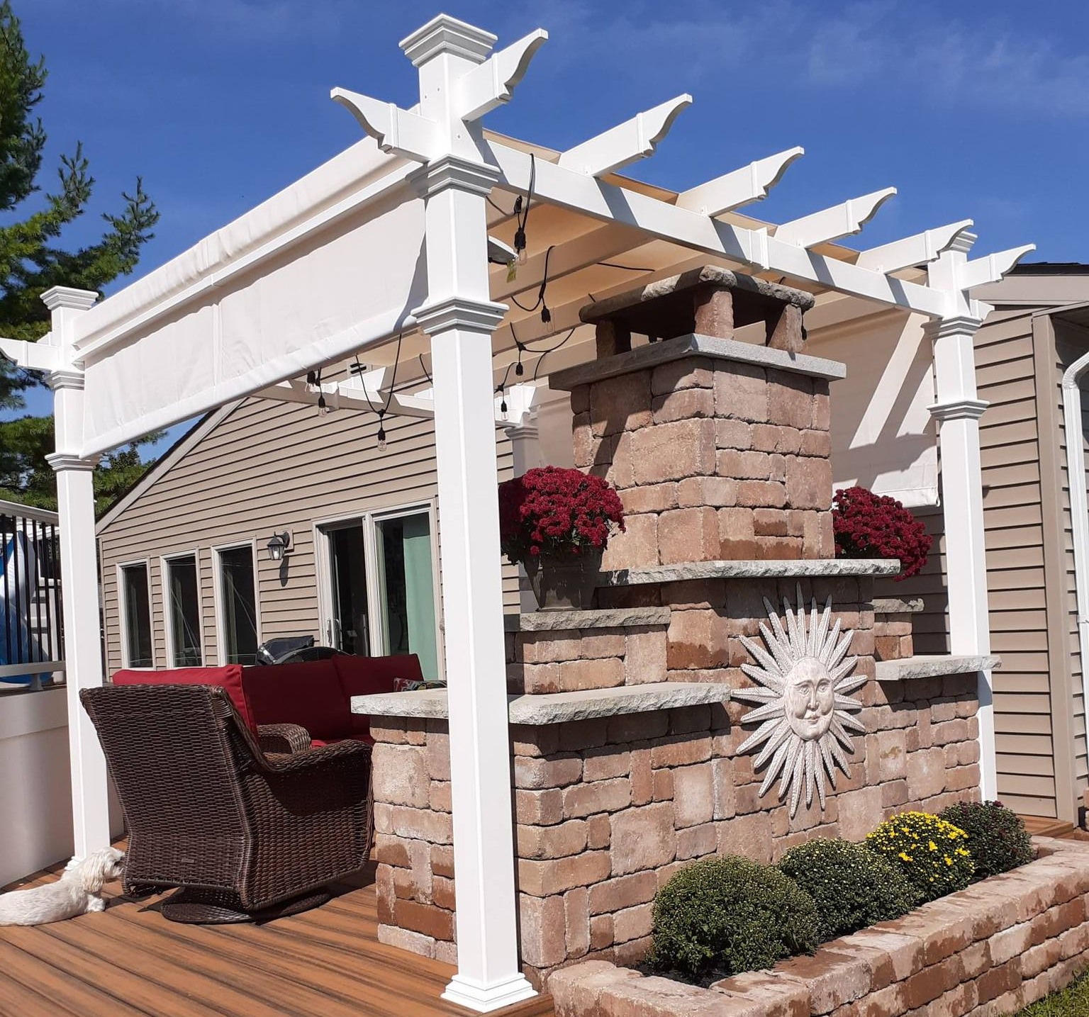 White gazebo in a lush garden beside a swimming pool and houses at sunset