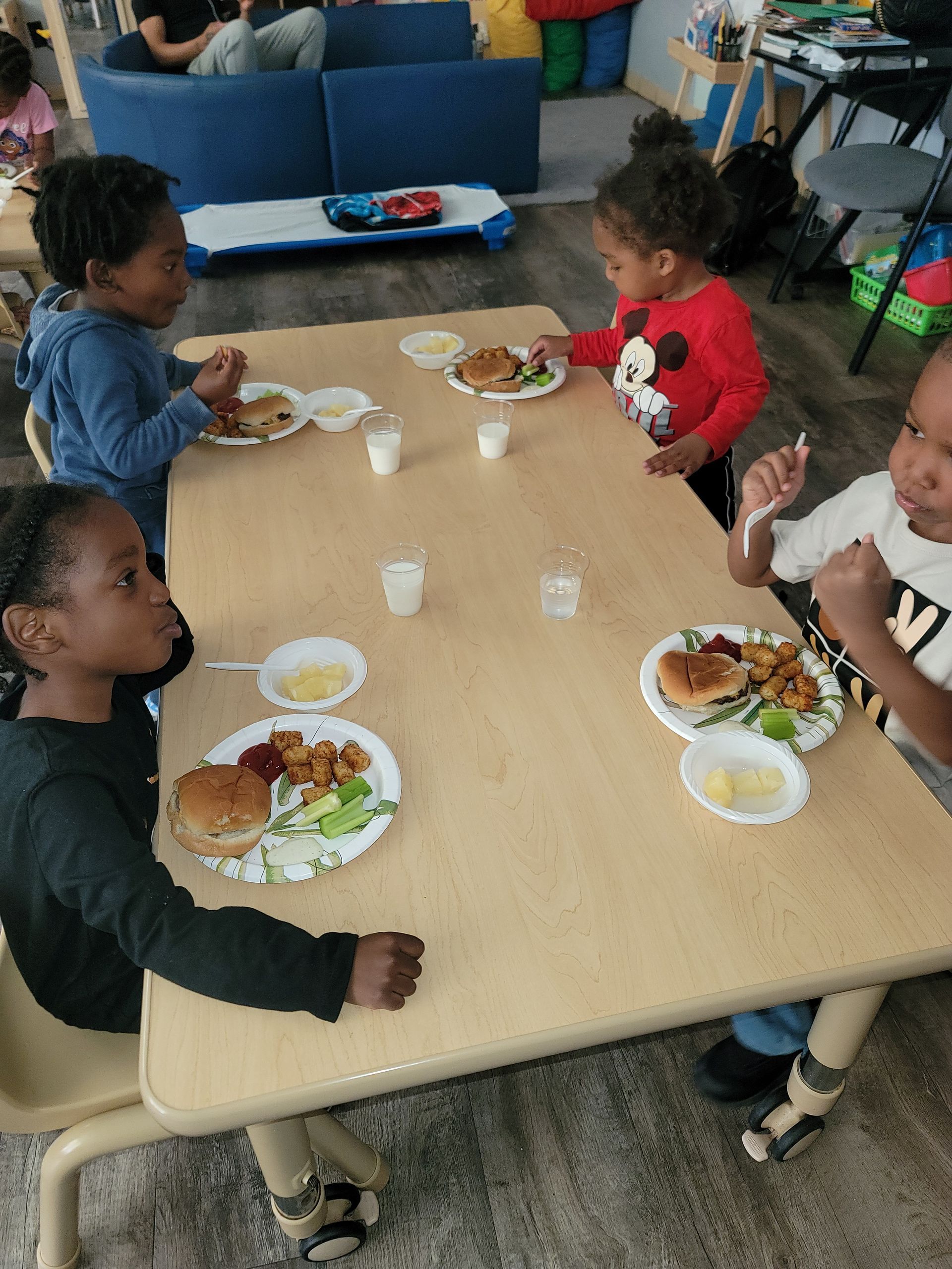 A Group of Children Are Sitting Around a Table Eating Food