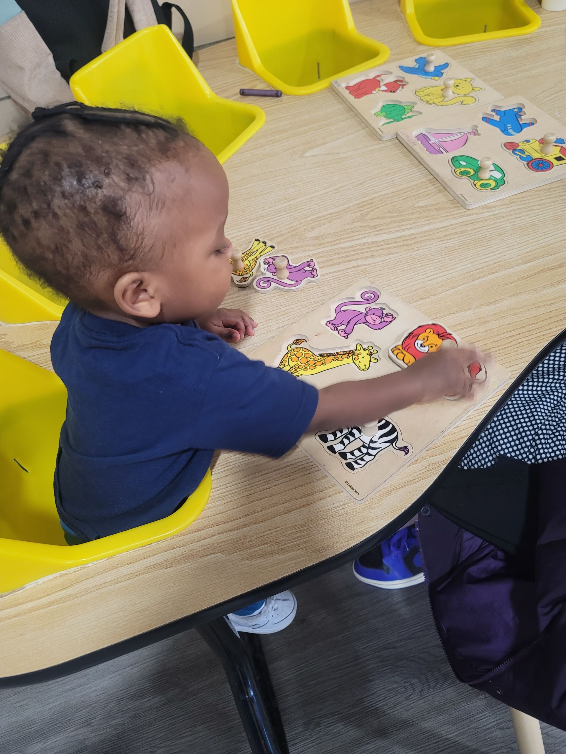 A little boy is sitting at a table playing with a puzzle.