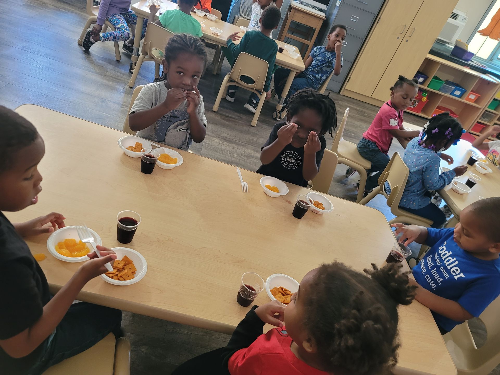A group of children are sitting at a table eating food.