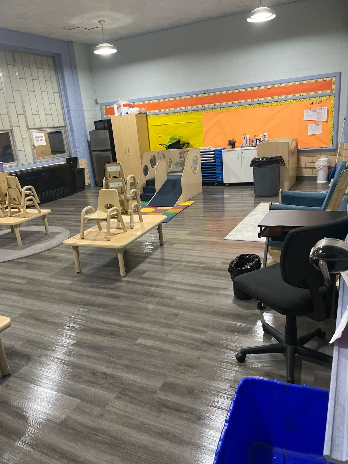 A classroom with wooden chairs , tables , and a desk.