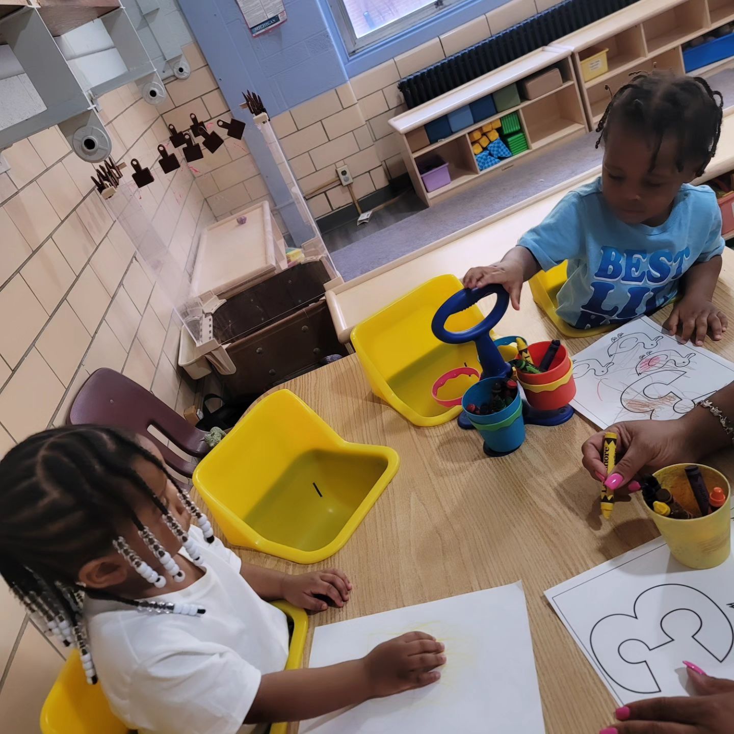 Two Little Girls Are Sitting at A Table Playing with Toys