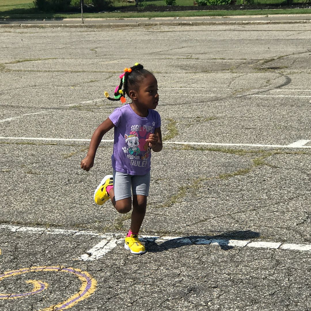 A Little Girl Is Running in A Parking Lot