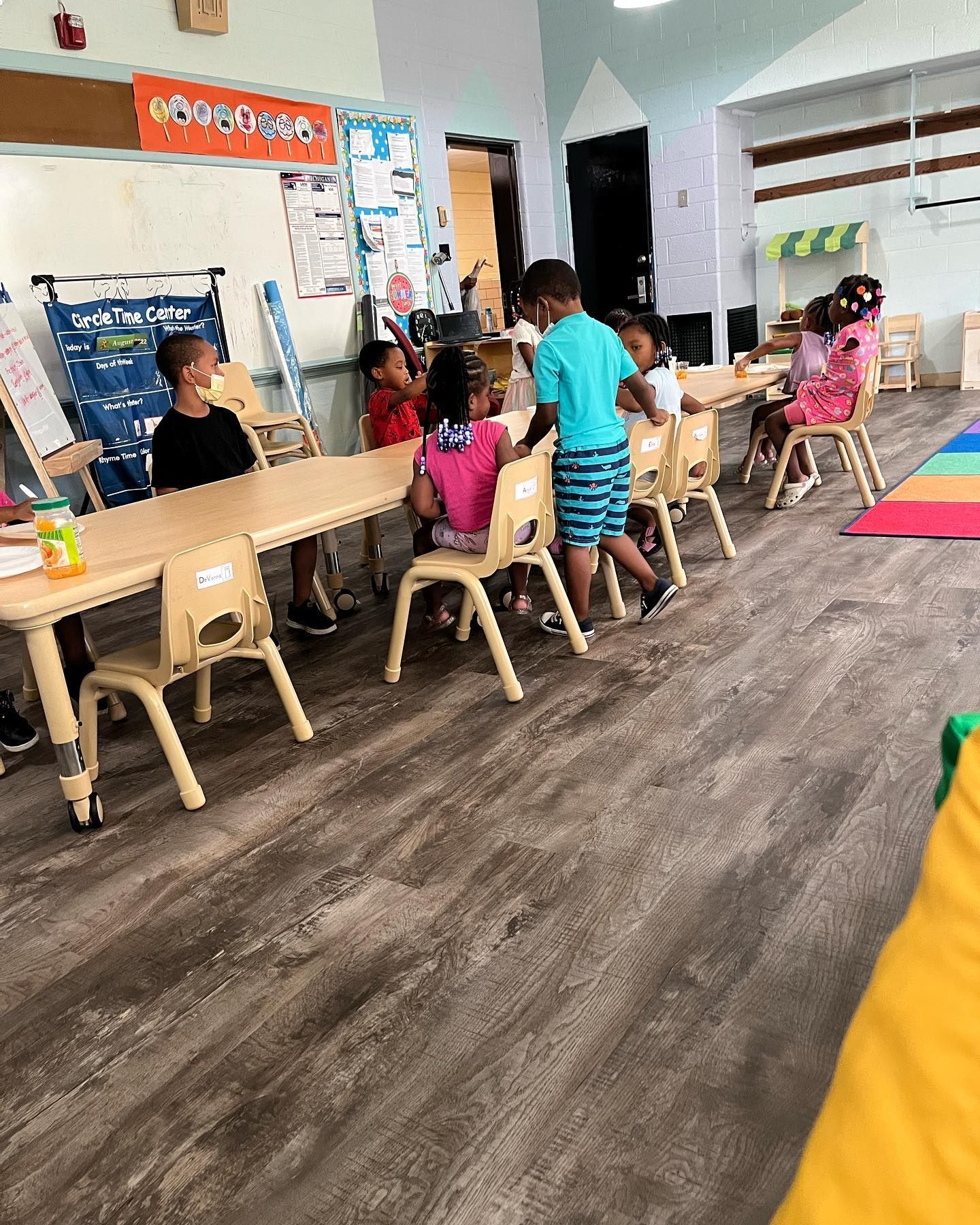A Group of Children Are Sitting at Tables in A Classroom