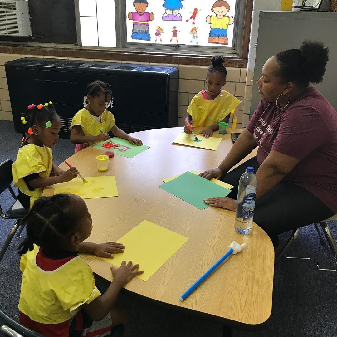 A Woman Is Sitting at A Table with A Group of Children