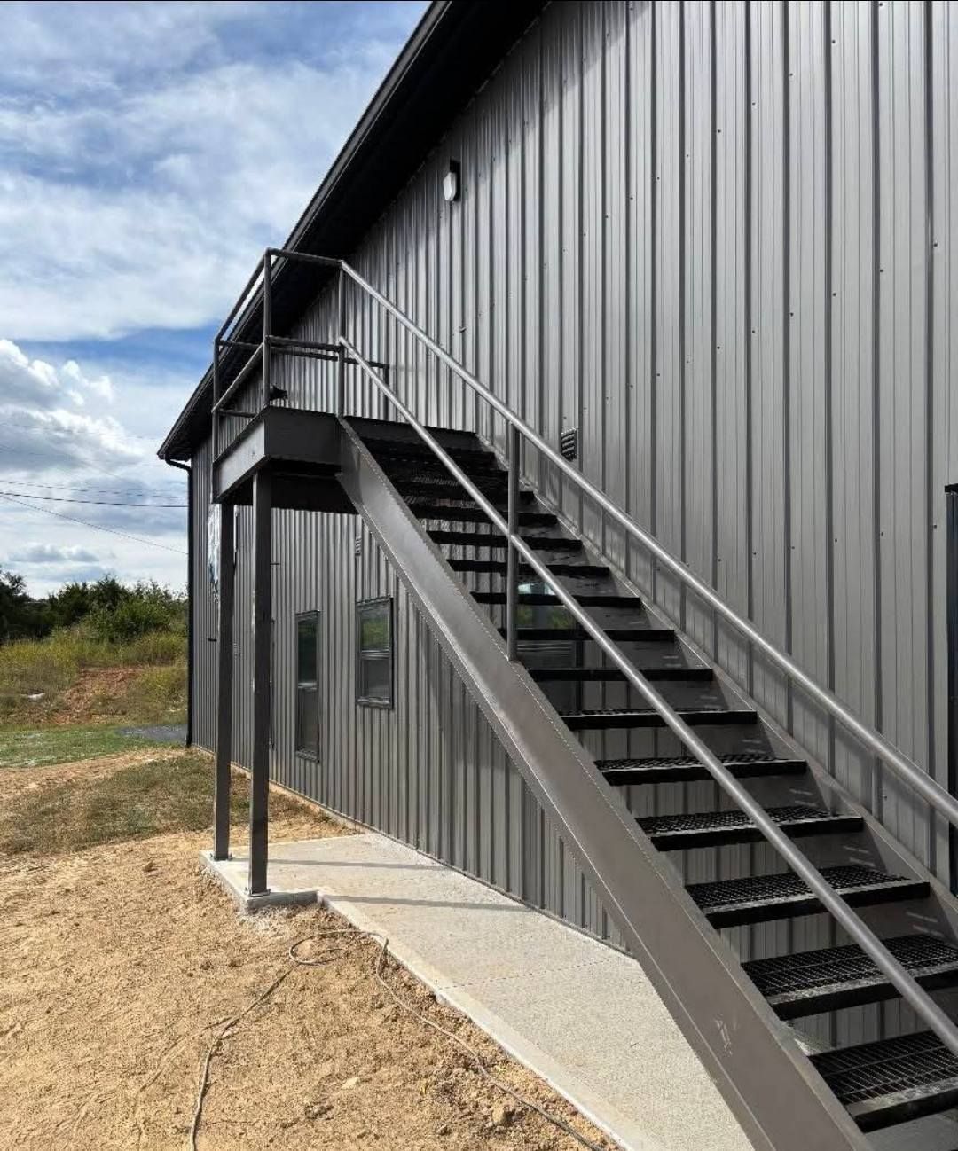 Gray metal exterior stairs next to a building with matching siding, on a cloudy day.