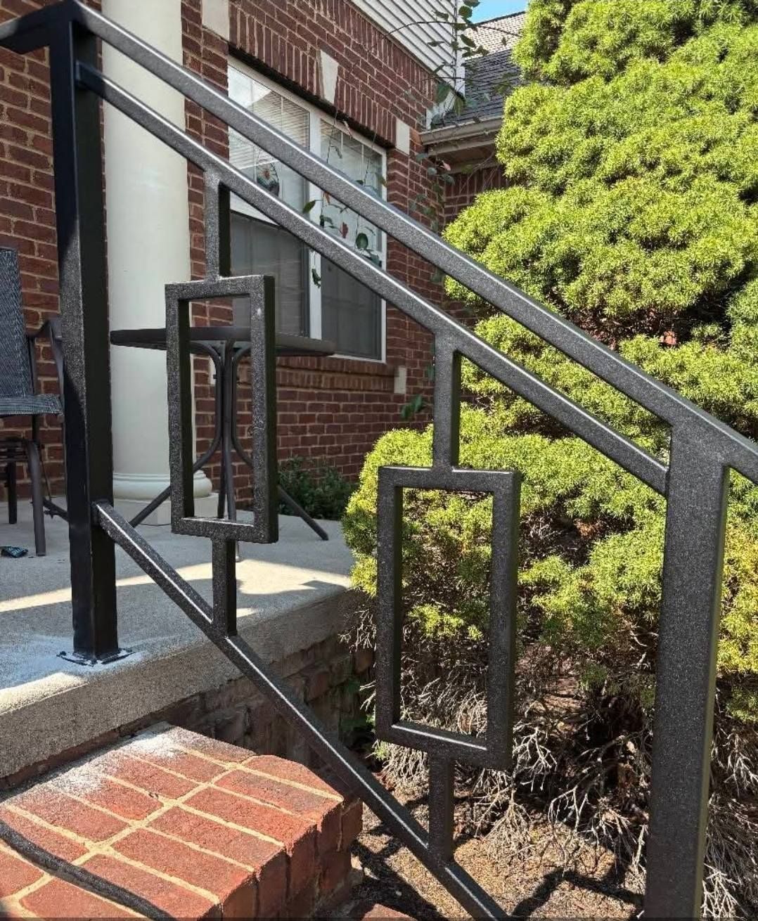 Black metal railing with rectangular decorative accents on brick steps.