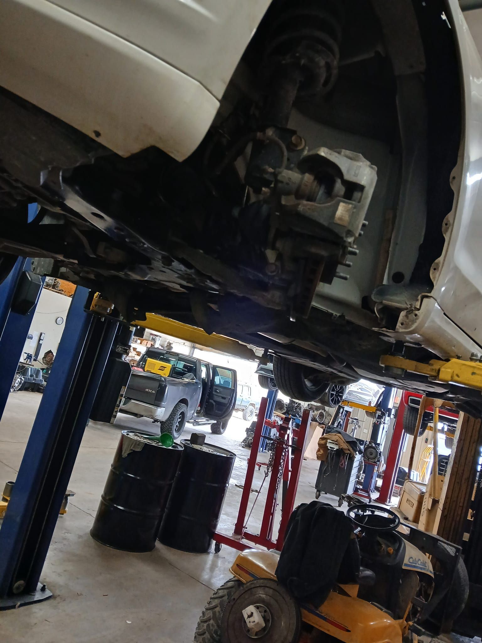 Car on a lift in a garage, undercarriage visible. A mechanic's workspace with tools and equipment in the background.