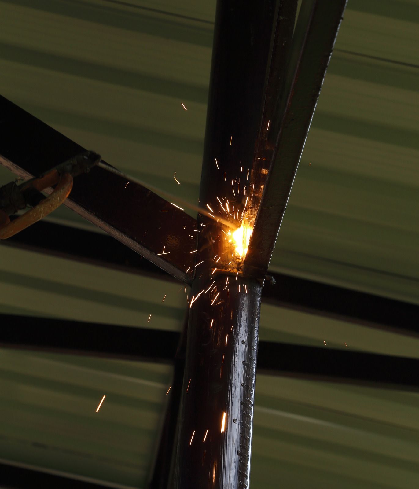 Welder joining two metal beams with sparks flying.