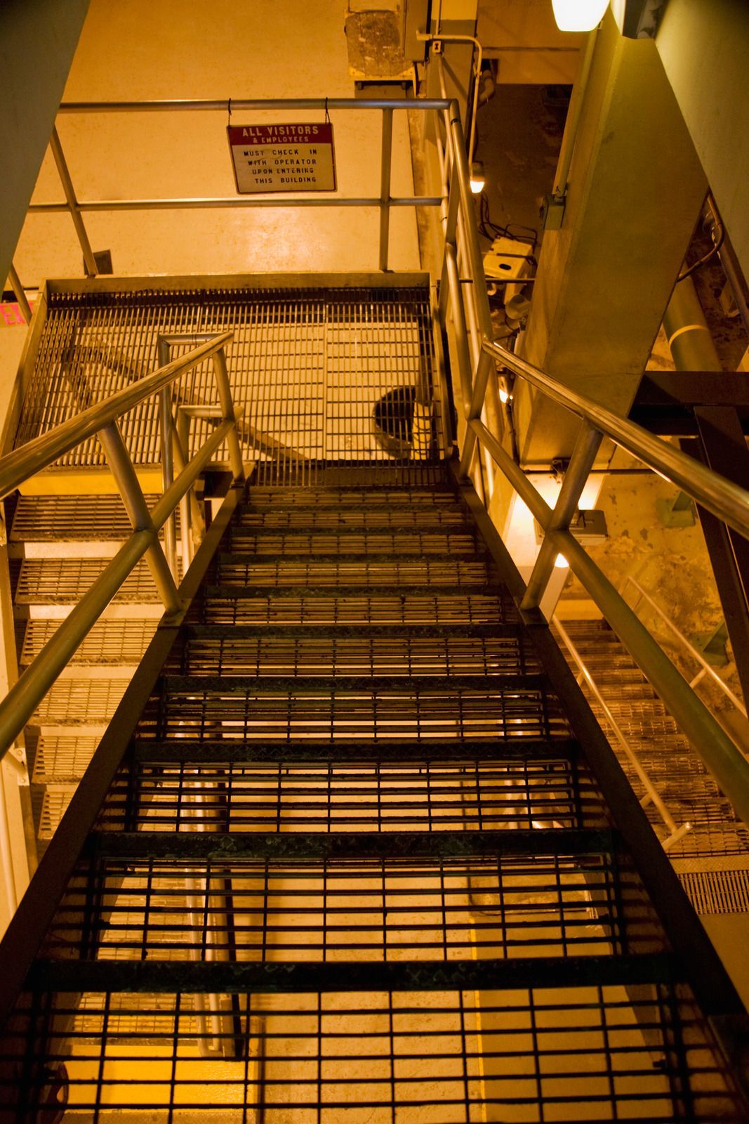 Metal staircase leads upwards in an industrial setting, viewed from a low angle.