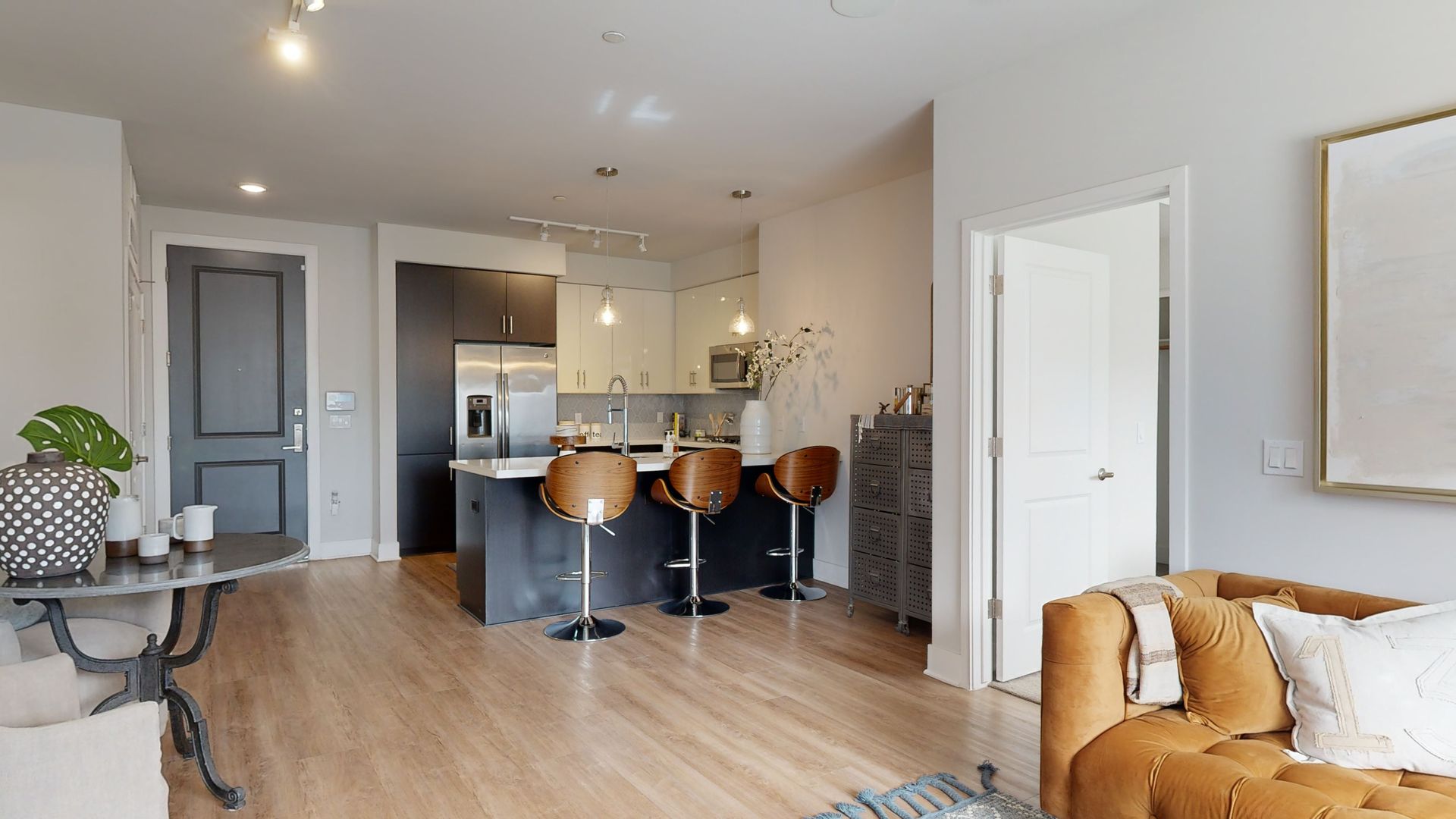 A living room with a couch , table , chairs and a kitchen.