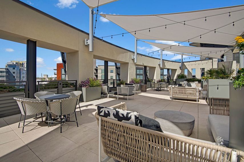 A rooftop patio with tables , chairs , and umbrellas.