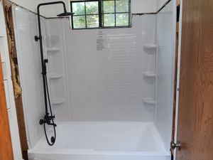 A bathroom with a bathtub , shower , and window.