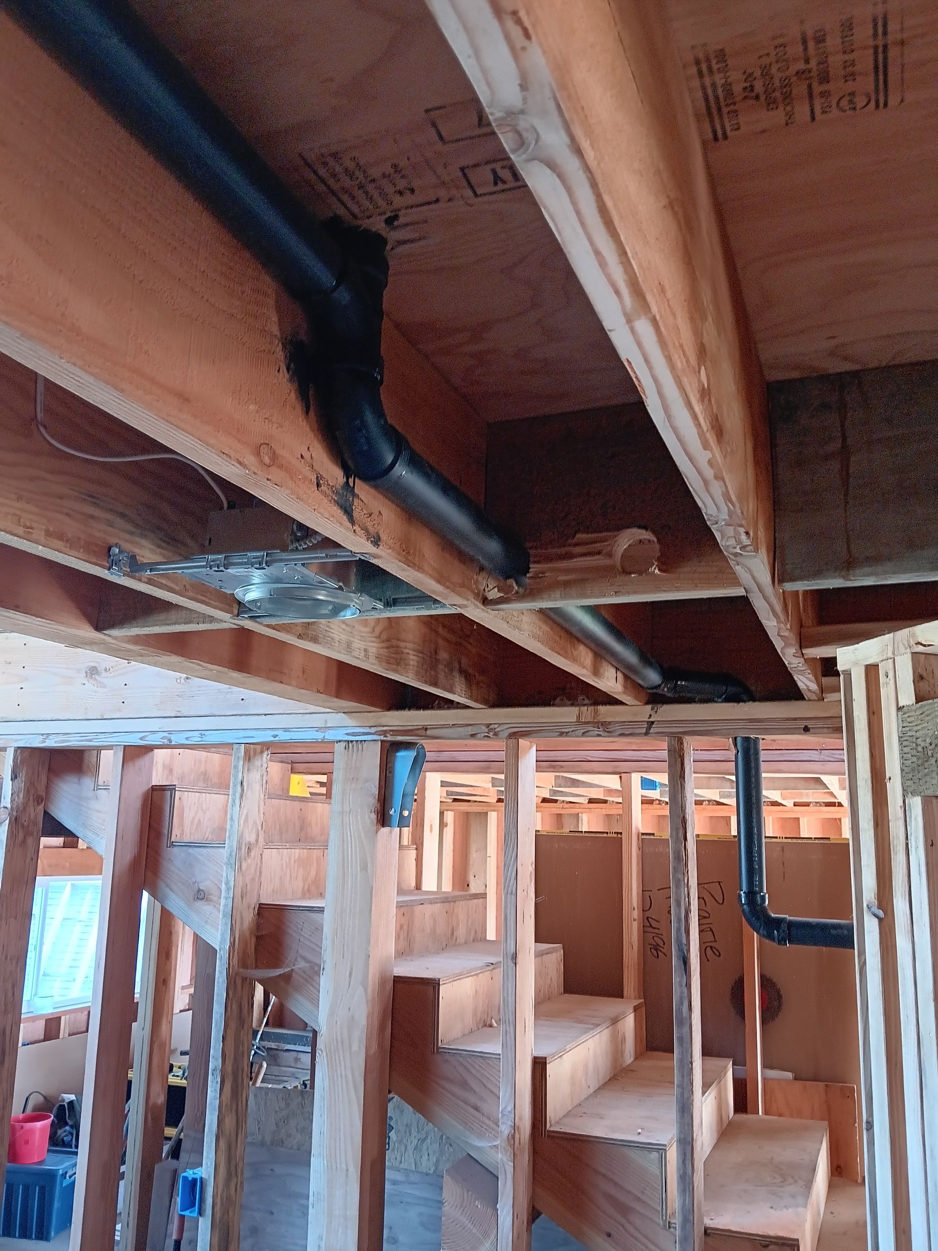 Unfinished basement framing with exposed wooden beams, ducts, and open wall studs