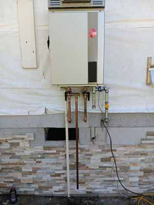 A peer brand water heater is attached to a brick wall