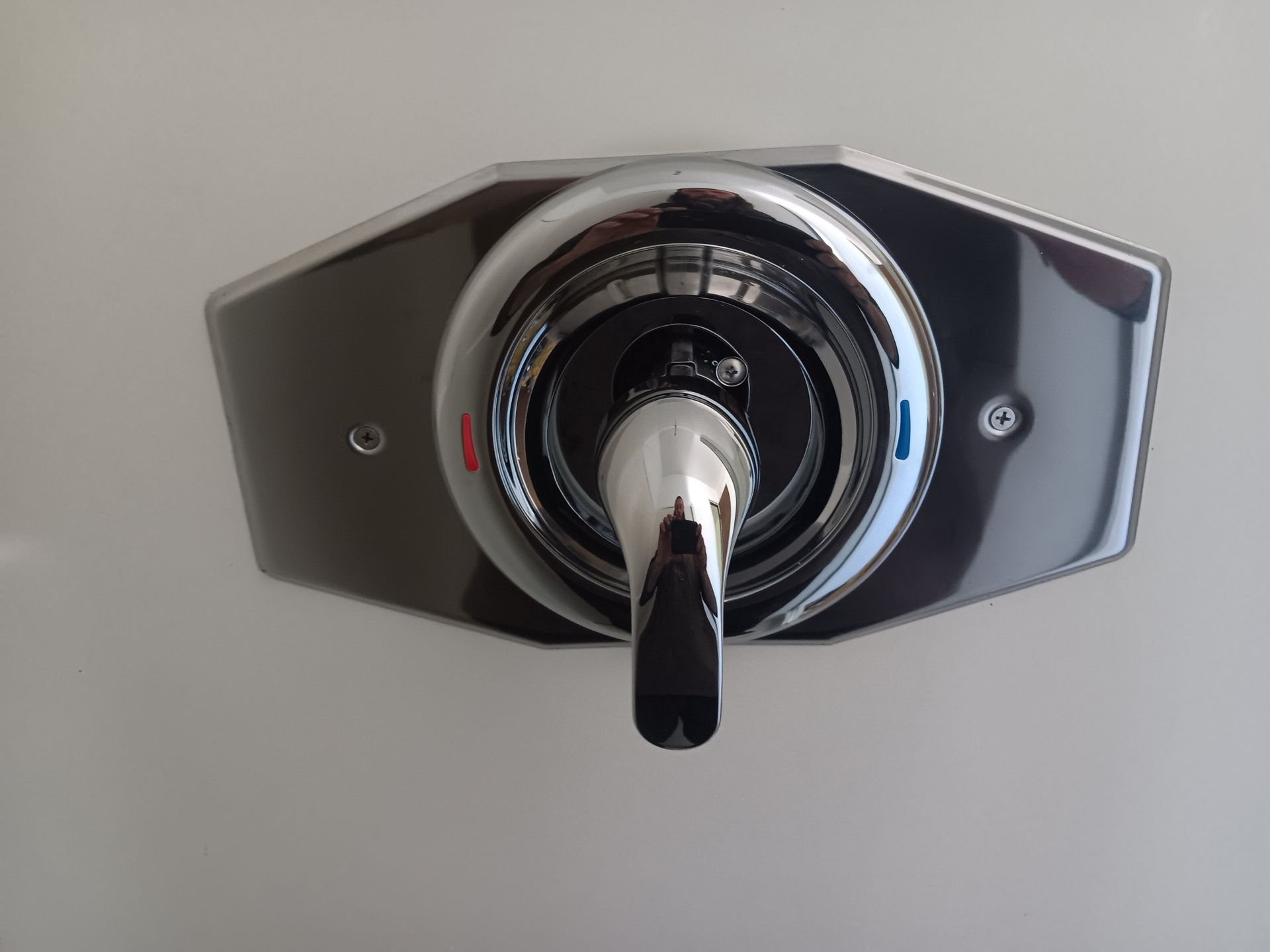 A close up of a chrome faucet on a white wall