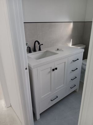 A bathroom with a white vanity , sink and toilet.