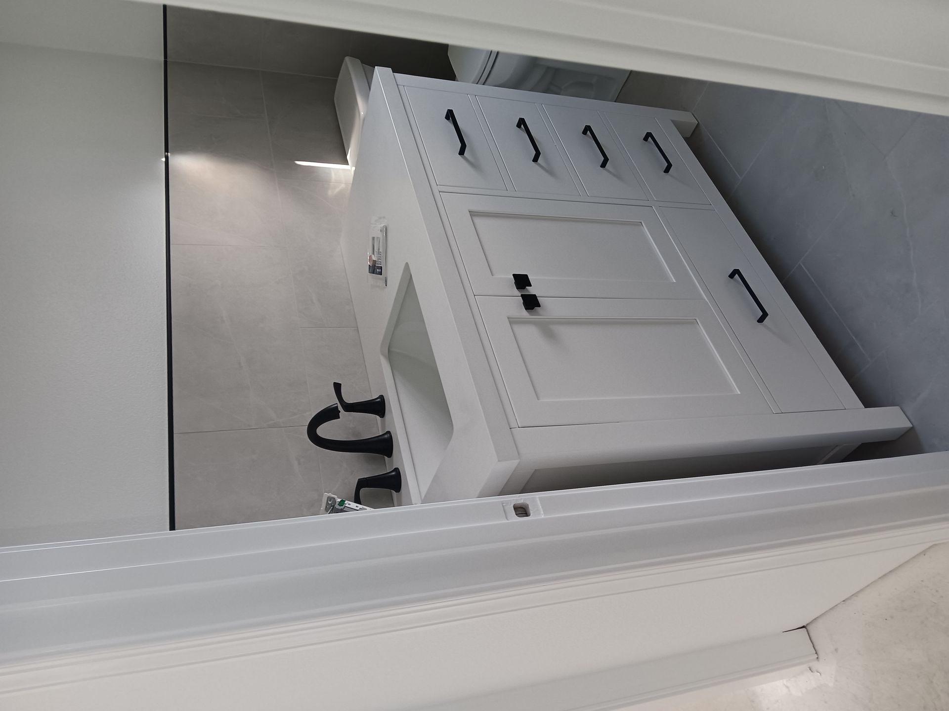 Tilted white door or panel in a metallic interior space with a black cable visible behind it